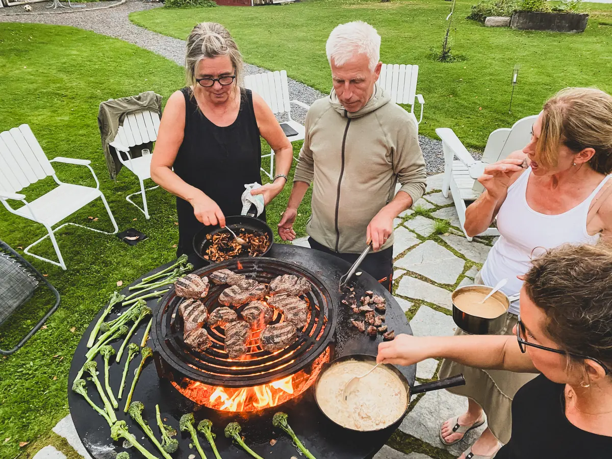 Delägarna lagar mat tillsammans vid en stor grill under en friluftsdag