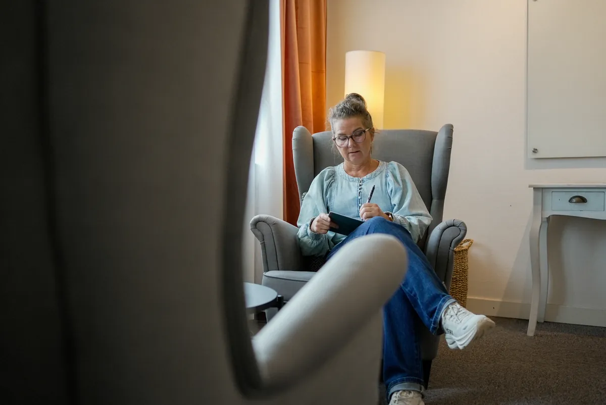 Synnöve Orebjörk, Din Utveckling, antecknar i fåtöljen i sitt kontorsrum